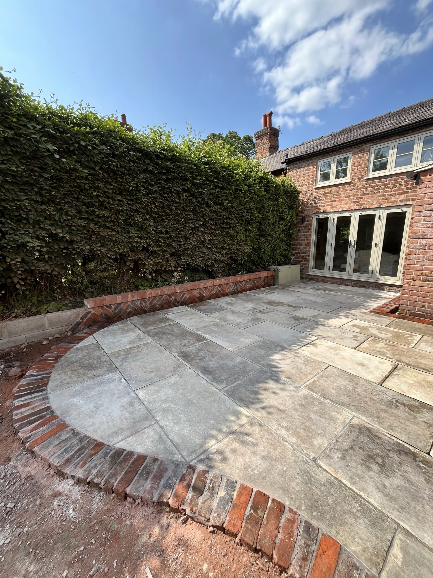 Sandstone patio under construction — a sweeping curved edge being set to line and level on a fresh sub-base
